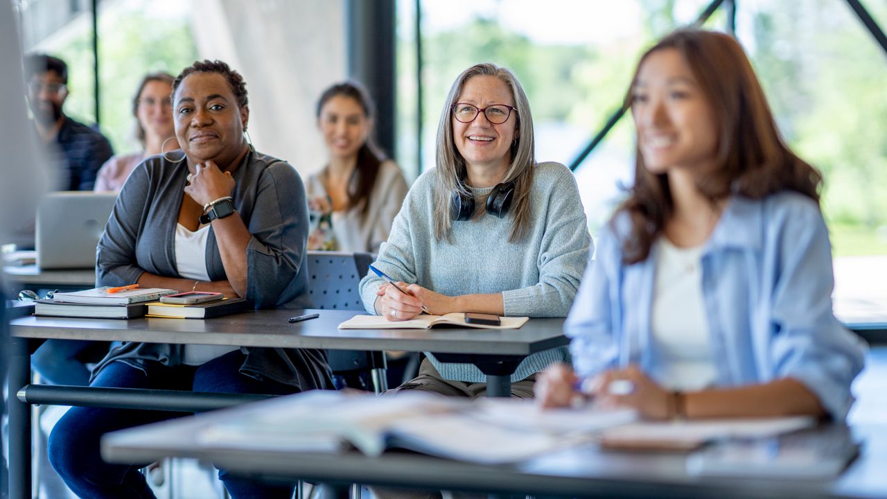 women sitting at tables listening to a speaker