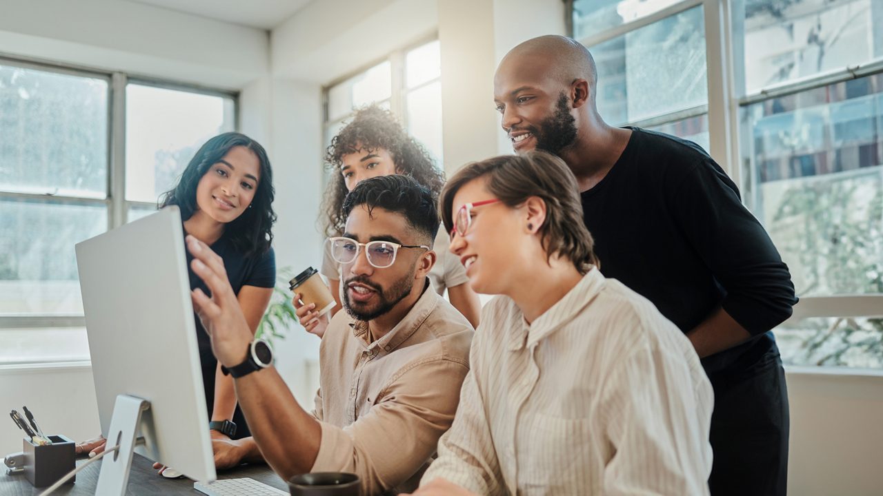 a group of people gather around a computer