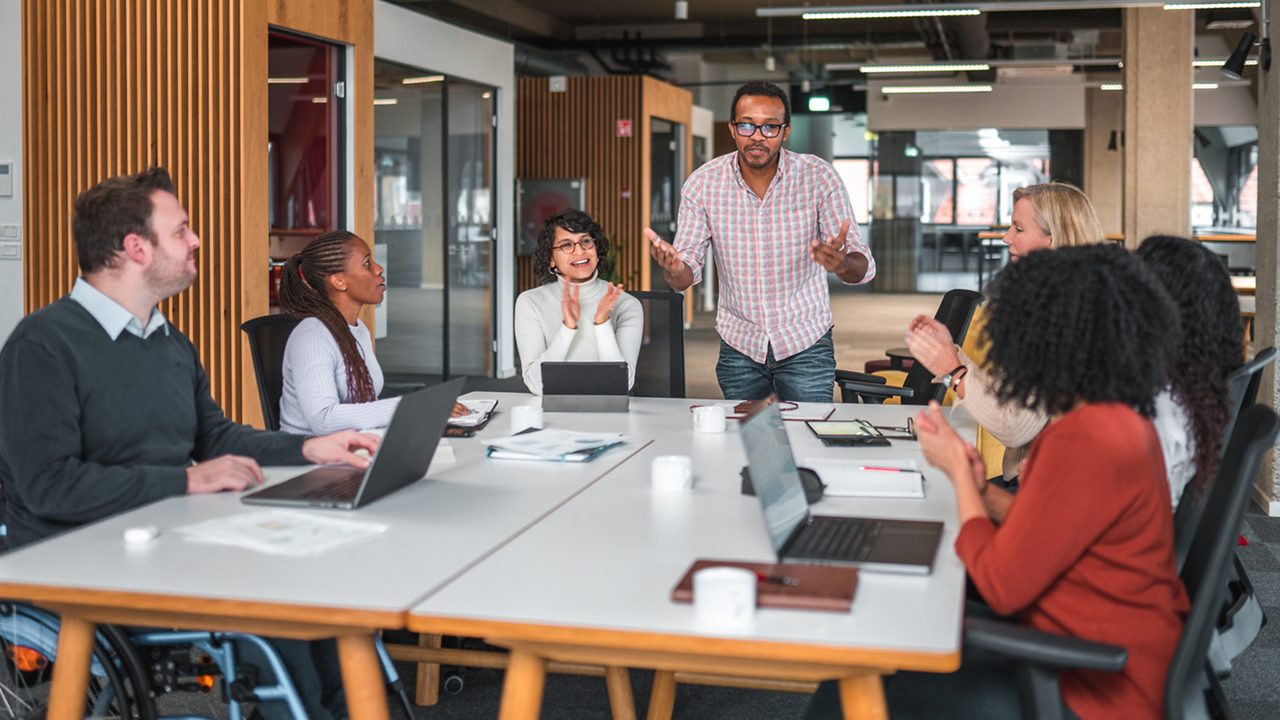 a group of coworkers meeting around a table in a modern office