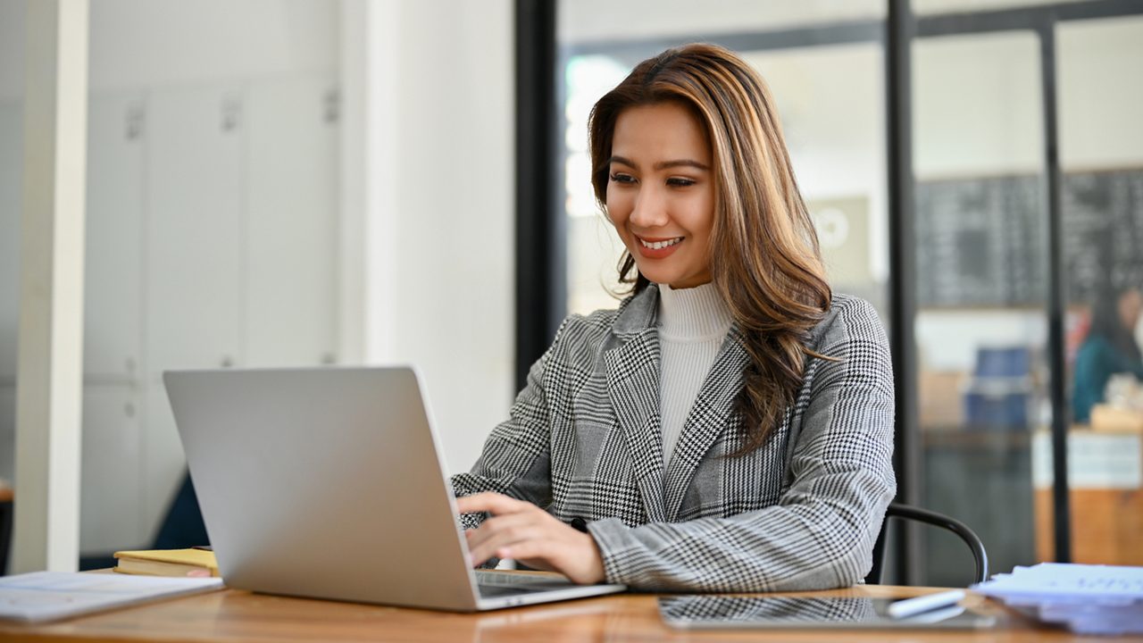 woman smiles while using laptop in an office