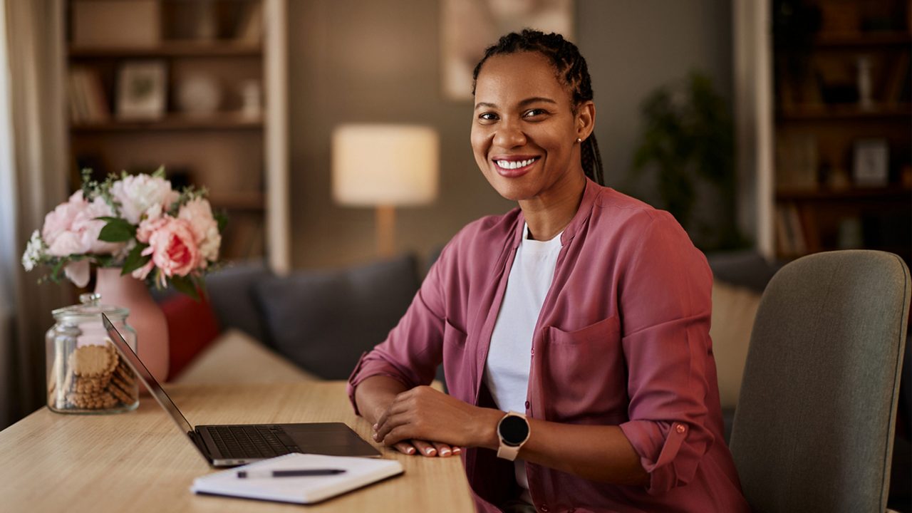 woman smiling in front of a laptop at home