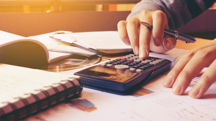 A person is using a calculator on a desk.