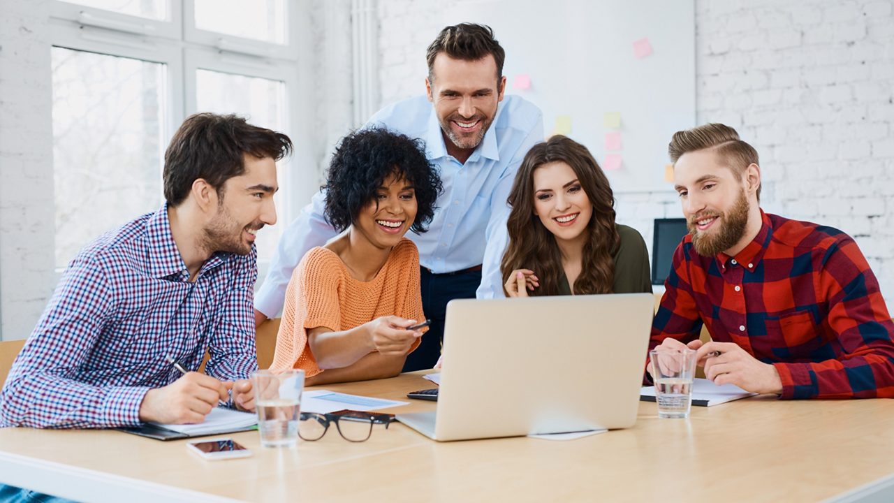 Team members collaborate over a laptop.