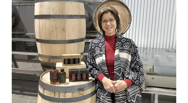 Jolene from Wabanaki Maple standing near maple barrels
