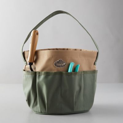 Green canvas garden utility bag filled with garden tools.