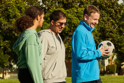 Three people walking in a park, discussing personal goals for budgeting.