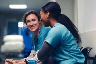 Two female healthcare professionals discuss their goals during their busy workday.