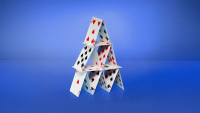 Playing cards built into a house of cards with a blue background.