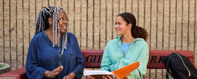Mentor and student converse on bench.