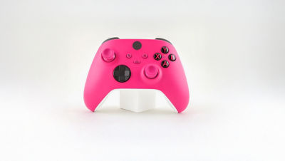 Pink video game controller on a white stand.