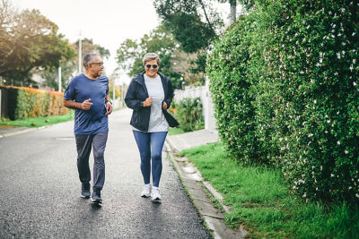 A man and woman jogging down a tree-lined street