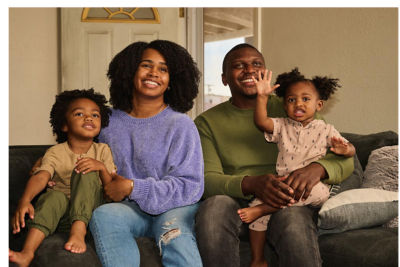 A family sitting together on a couch smiling