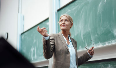 female teacher standing in front of chalk board
