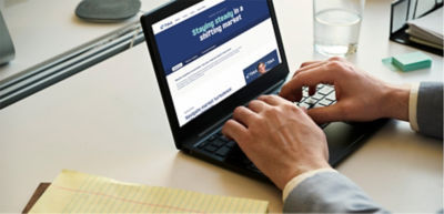 image of a man sitting at a desk looking at TIAA’s Market Volatility  web page on a laptop