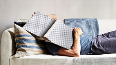 Person laying on a couch with a polka dot covered book over their face