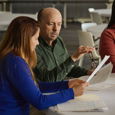 a group of people sitting at a table looking at papers