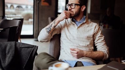 A man sitting in a café having a cup of coffee, in deep thought.