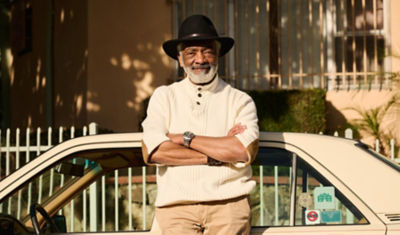 A man stands proudly in front of his car