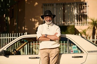 A man stands in front of his car smiling