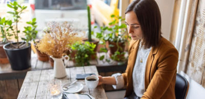 Smiling man with gray hair and blue glasses wearing a dark suit in an office setting