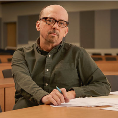 Male student sitting at desk in empty classroom