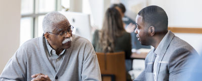 Older man and younger man sitting at a table discussing estate planning 