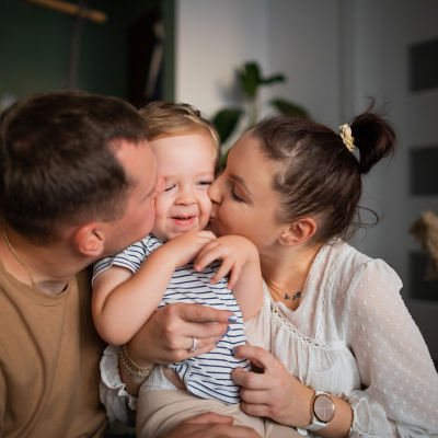 A man and a woman kiss a baby who will be their primary beneficiary.