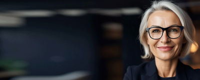 Professional woman with silver hair and glasses, representing TIAA's asset manager Nuveen.