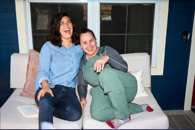 Two women sitting on a couch laughing