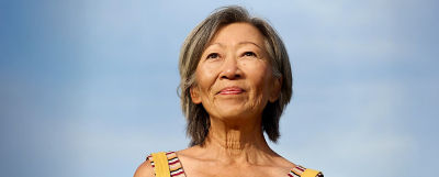 Confident senior woman against blue sky, symbolizing security and peace in retirement with TIAA.