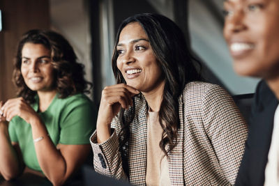 Two women dressed in business attire smiling away from the camera.