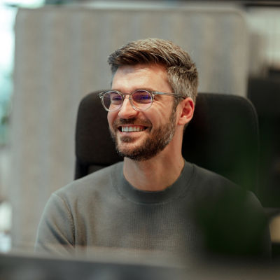 Man with clear glasses smiling.