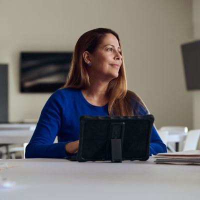 Woman sitting at a tablet staring off to the side smiling