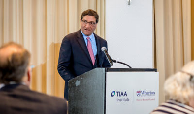 TIAA Institute lead speaking at podium during financial education event. 