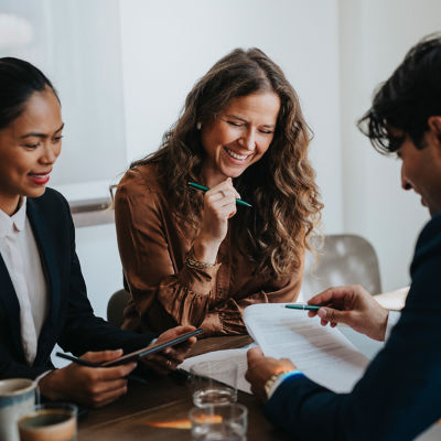 Three people sitting at a desk discussing paperwork