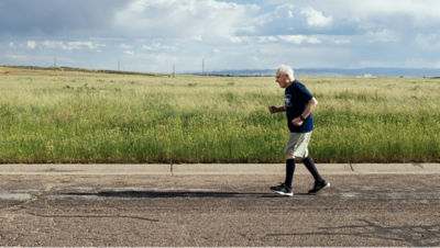 104-year-old-man running on a road with a field in the background
