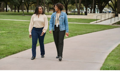 Two female educators take some time for a walk on the grounds of their university.