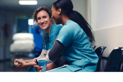 Two female healthcare professionals take a breather during their busy workday to catch up with each other.
