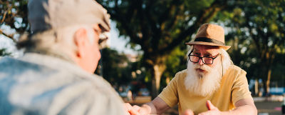 Two elderly men sitting at a table playing an abstract strategy board game