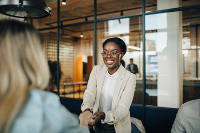 Woman in a tan blazer talking to a retirement plan sponsor.