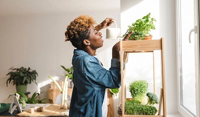 A woman watering a potted plant.