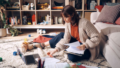 Woman sitting on the floor working with a laptop and paperwork