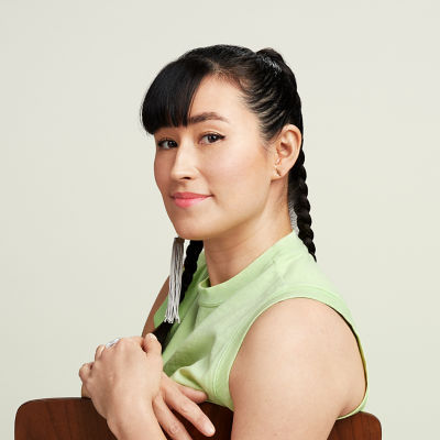 A young lady siting in a chair with her arms draped over the chair back.