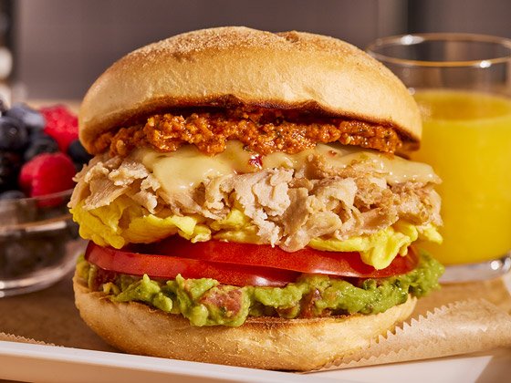 Chicken Sandwich Slices, tomatoes, pepperjack cheese, guacamole, sundried tomato sauce and chives served on a bun and orange juice on the side