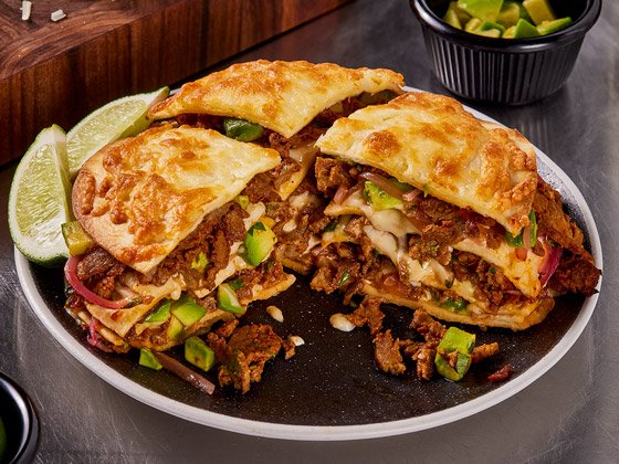 Plated steak birria tortizza with avocado and lime