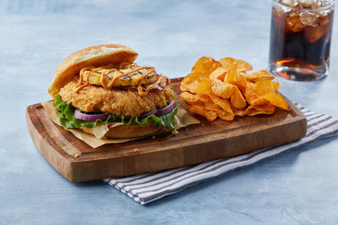sweet and spicy chicken sandwich with chips and a drink.