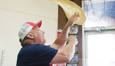 Pizza operator tossing and flipping pizza dough image