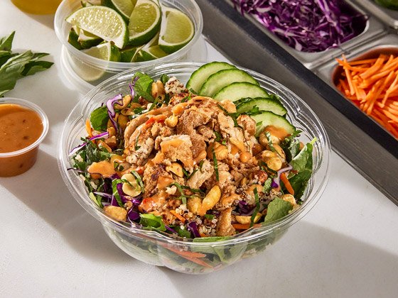 Chicken bowl with kale, cabbage, carrots, cucumbers, peanuts and a peanut lime sauce on the side