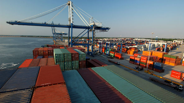 Overhead view of multiple shipping containers on a ship and in a loading dock
