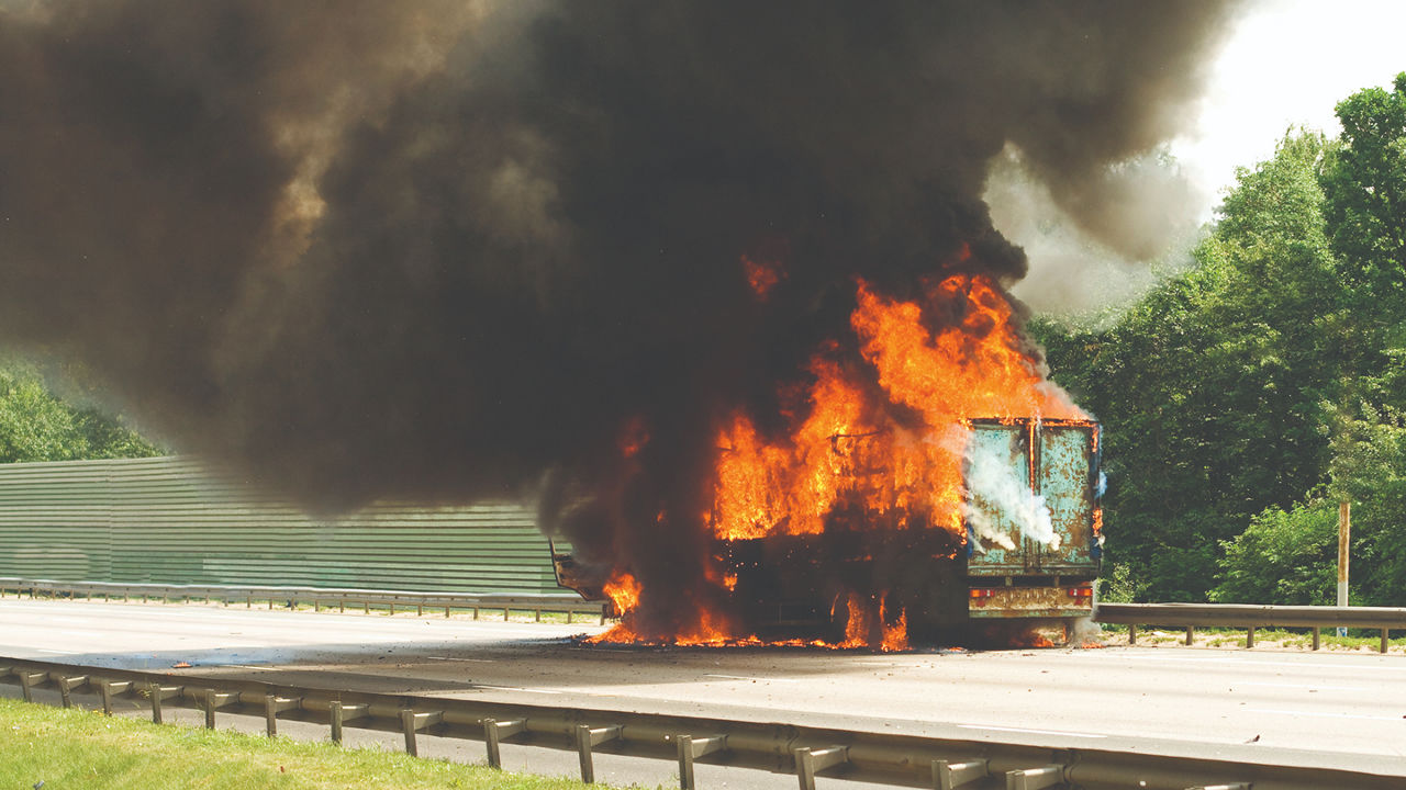 Semi truck on fire on the side of the highway. 